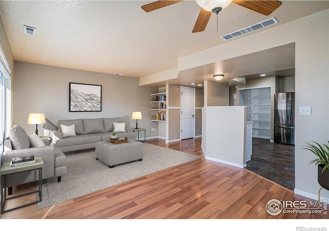 living room featuring a textured ceiling, dark hardwood / wood-style floors, and ceiling fan