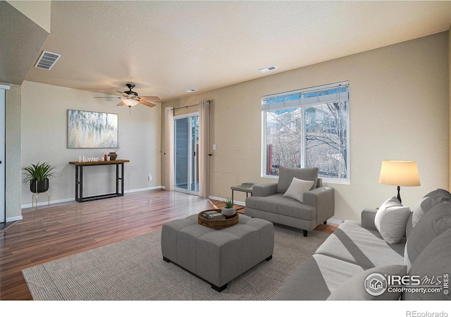 living room featuring hardwood / wood-style flooring, ceiling fan, and a textured ceiling