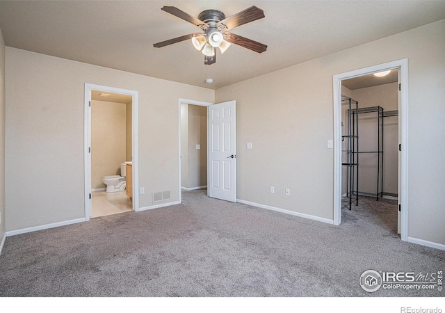 unfurnished bedroom featuring ceiling fan, light colored carpet, and connected bathroom