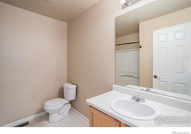 bathroom with vanity, toilet, and a textured ceiling