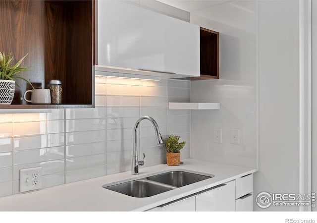 kitchen with tasteful backsplash, white cabinetry, and sink