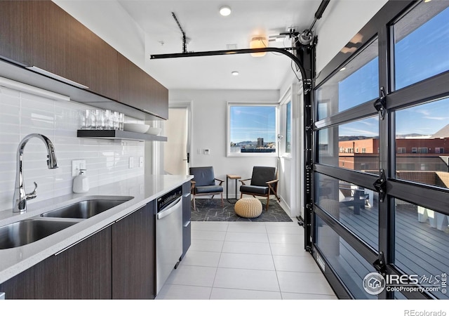 kitchen with backsplash, dark brown cabinets, sink, dishwasher, and light tile patterned flooring