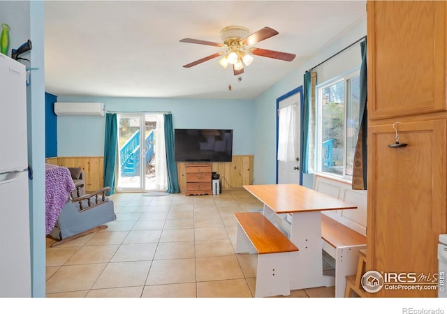 interior space with ceiling fan, light tile patterned floors, wooden walls, and a wall mounted AC