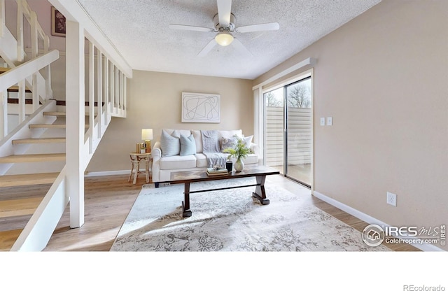 living room with ceiling fan, light hardwood / wood-style floors, and a textured ceiling