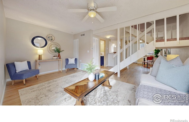 living room featuring ceiling fan, wood-type flooring, and a textured ceiling