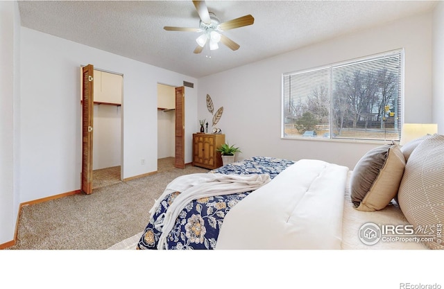 bedroom featuring ceiling fan, a spacious closet, light colored carpet, a textured ceiling, and a closet