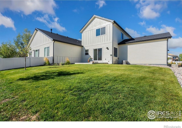 back of house featuring fence, board and batten siding, and a yard