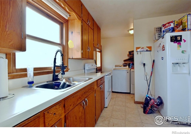 kitchen with white appliances, sink, and separate washer and dryer