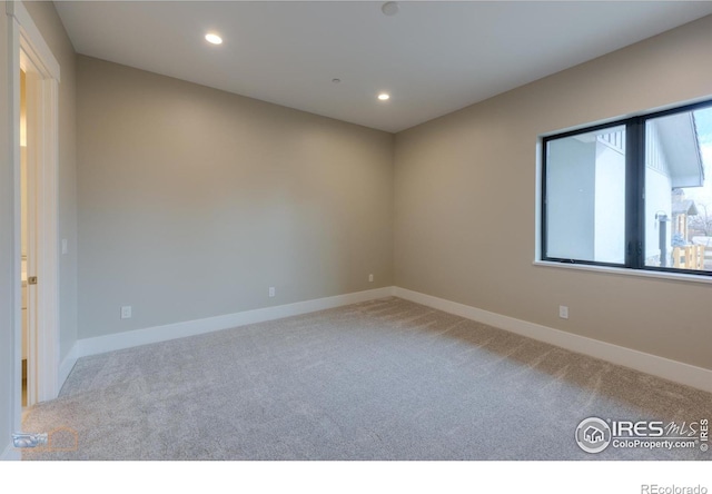 empty room with baseboards, recessed lighting, and light colored carpet