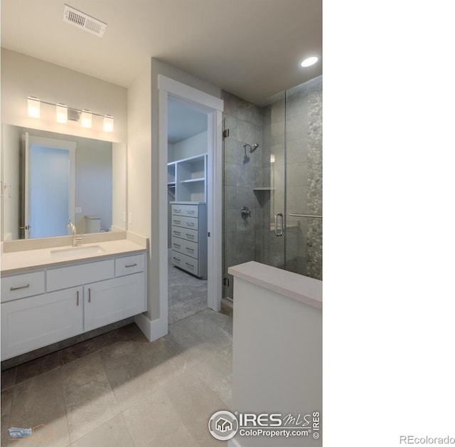 full bath featuring a walk in closet, recessed lighting, visible vents, a stall shower, and vanity