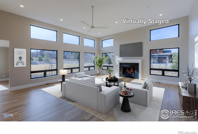 living room featuring plenty of natural light, a premium fireplace, a high ceiling, and recessed lighting