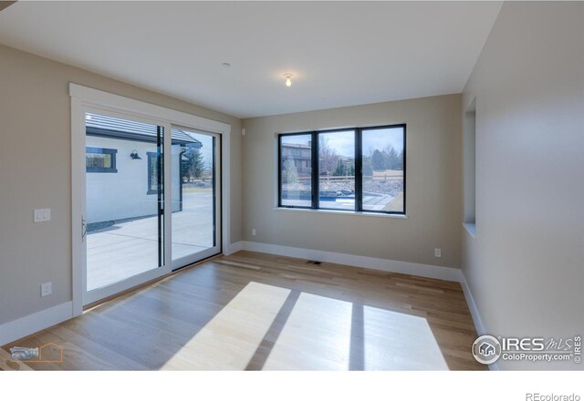 unfurnished room featuring light wood-style flooring, a wealth of natural light, and baseboards