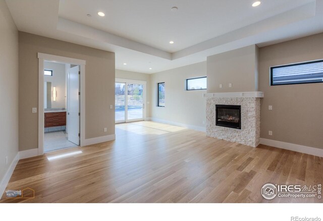 unfurnished living room featuring baseboards, a glass covered fireplace, and light wood-style floors