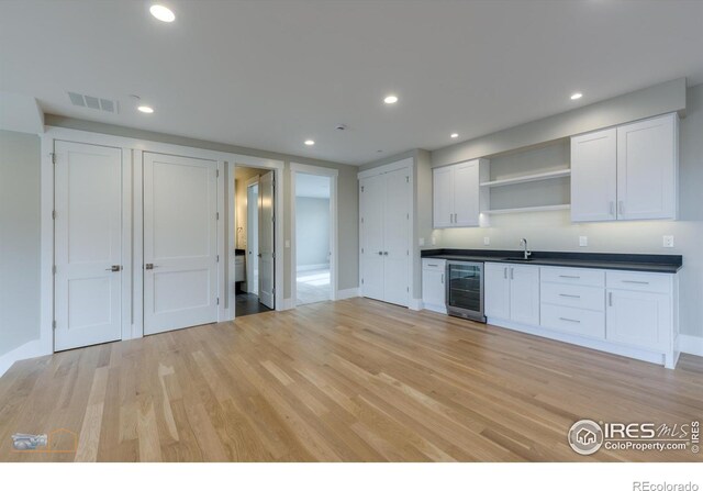 kitchen featuring dark countertops, wine cooler, light wood-style floors, white cabinetry, and open shelves