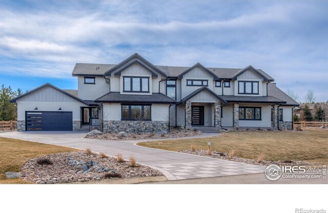 view of front facade featuring a garage, a front yard, stone siding, and concrete driveway