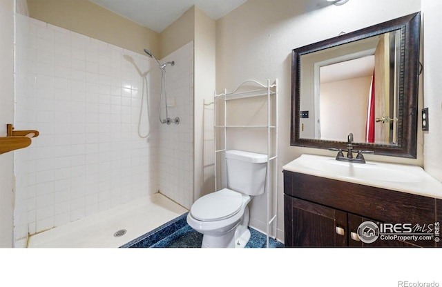 bathroom with a tile shower, vanity, and toilet