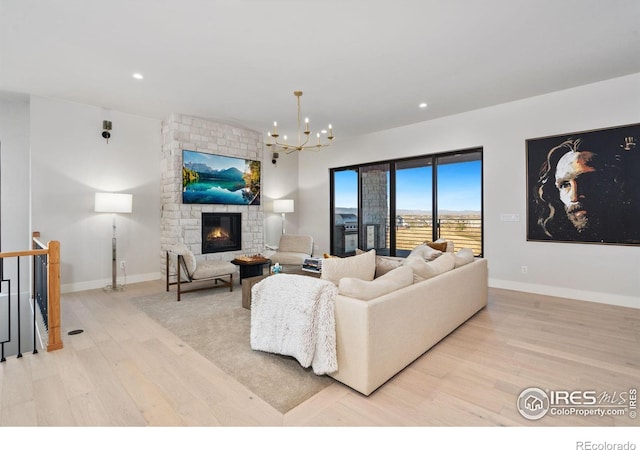 living room featuring a notable chandelier, light wood-type flooring, and a fireplace