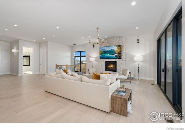 living room featuring a notable chandelier, light wood-type flooring, and a fireplace