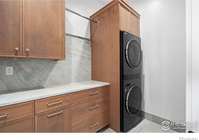 clothes washing area featuring cabinets, stacked washer / drying machine, and light tile patterned flooring