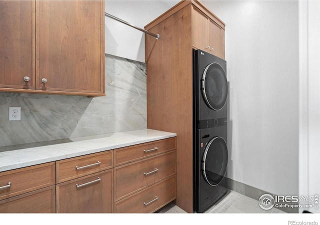 1722 Fire Glow Dr, Windsor, CO 80550 - laundry area with stacked washer / dryer, cabinet space, and light tile patterned floors