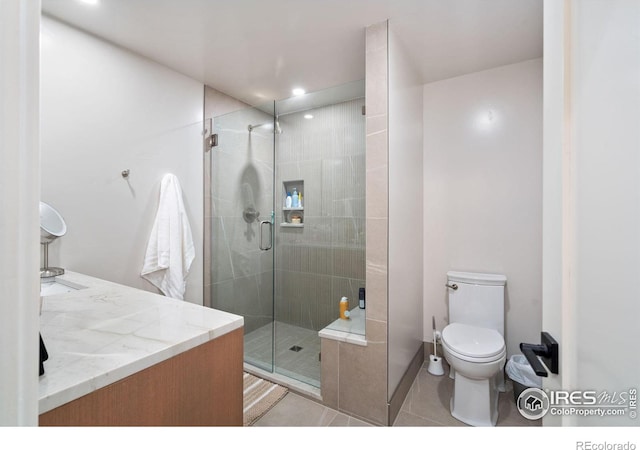 bathroom featuring tile patterned flooring, vanity, toilet, and a shower with shower door