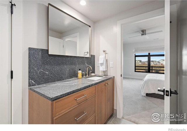 kitchen featuring light carpet, sink, decorative backsplash, ceiling fan, and dark stone countertops