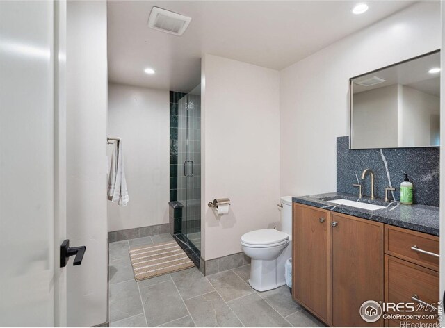 bathroom featuring vanity, a shower with door, tile patterned floors, toilet, and tasteful backsplash