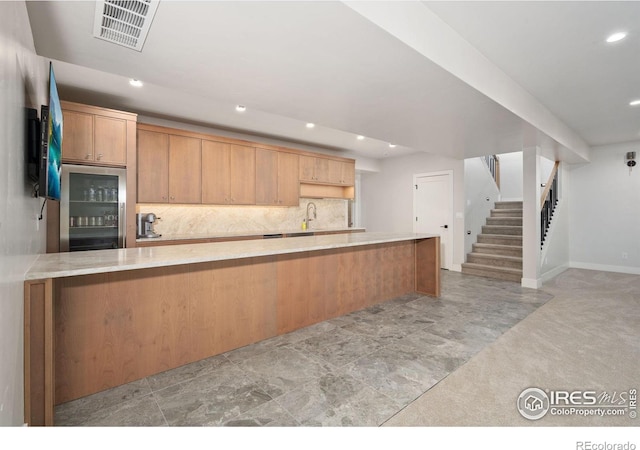 kitchen featuring light carpet, decorative backsplash, refrigerator, kitchen peninsula, and sink