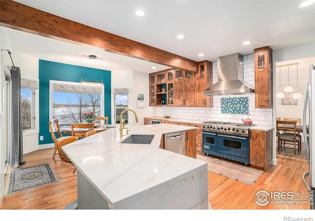 kitchen with beam ceiling, sink, stainless steel appliances, wall chimney range hood, and light hardwood / wood-style flooring