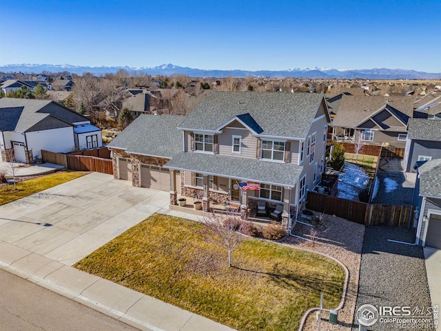 view of front of home featuring a mountain view, a garage, covered porch, and a front yard