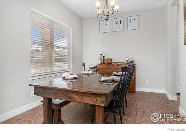 dining space with dark tile patterned floors and a notable chandelier