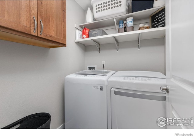 clothes washing area with washer and clothes dryer and cabinets