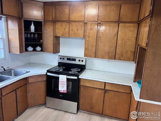 kitchen featuring electric range, sink, and light wood-type flooring