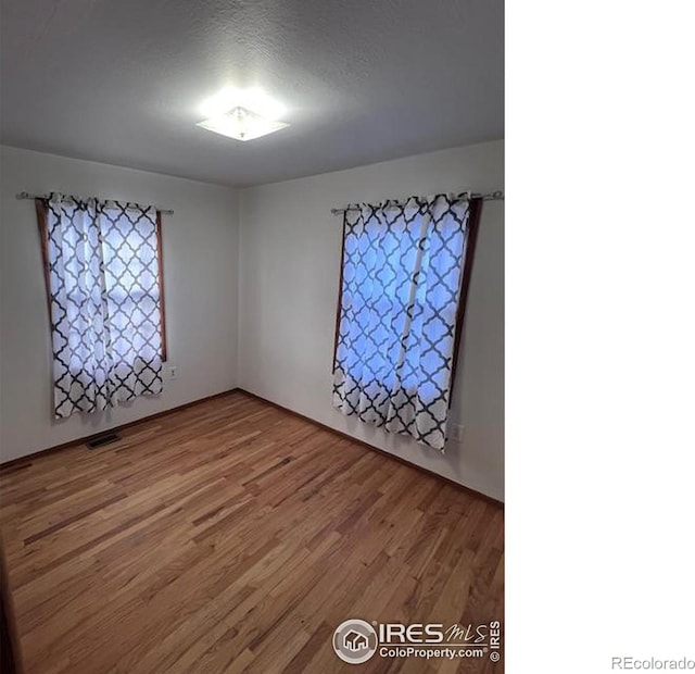 spare room with a textured ceiling and hardwood / wood-style flooring