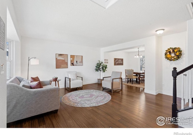 living room featuring a notable chandelier, dark hardwood / wood-style flooring, and a textured ceiling