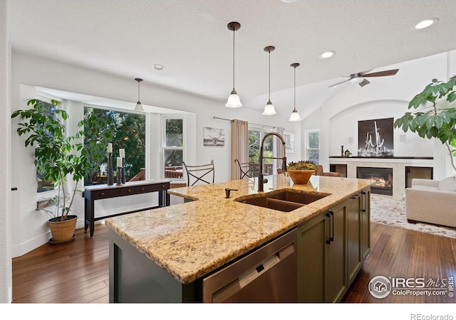 kitchen featuring light stone countertops, dishwasher, sink, pendant lighting, and a kitchen island with sink