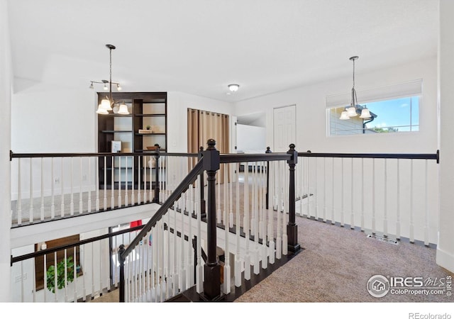 staircase featuring carpet flooring and a notable chandelier