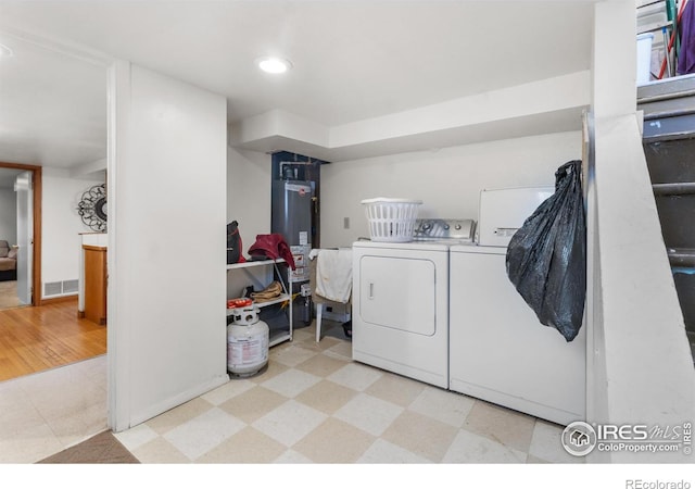 laundry area featuring light hardwood / wood-style floors, washing machine and dryer, and gas water heater