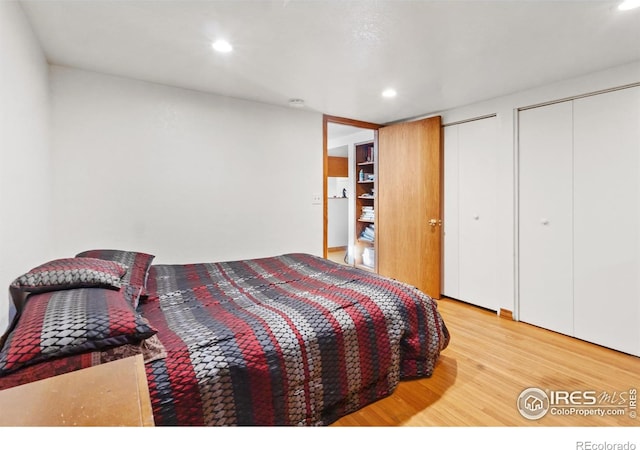 bedroom with two closets and light hardwood / wood-style floors