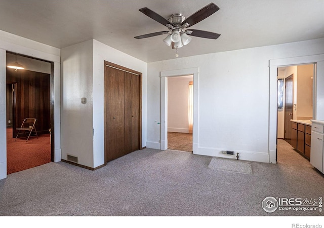 unfurnished bedroom featuring ensuite bath, ceiling fan, a closet, and light carpet