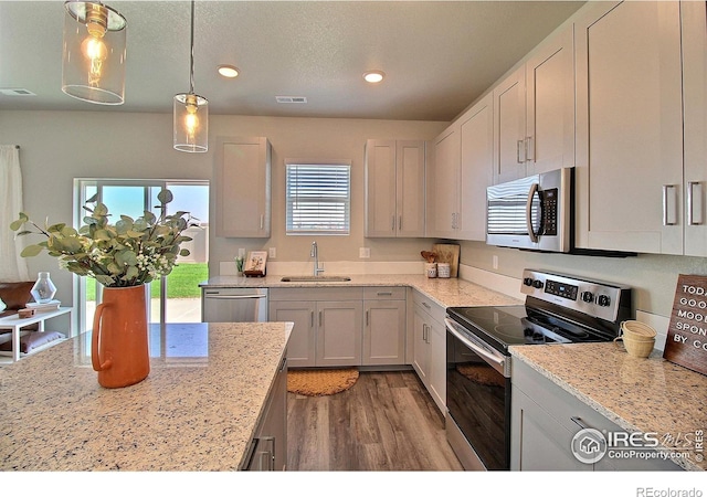 kitchen with light stone countertops, appliances with stainless steel finishes, sink, and white cabinets