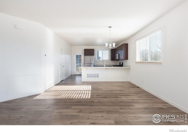 kitchen with plenty of natural light, dark hardwood / wood-style flooring, kitchen peninsula, and appliances with stainless steel finishes