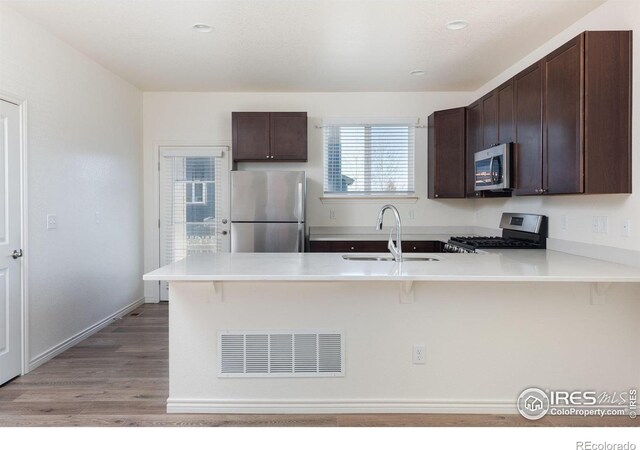 kitchen featuring a kitchen bar, kitchen peninsula, sink, and appliances with stainless steel finishes