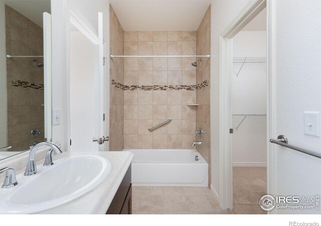 bathroom featuring tile patterned flooring, vanity, and tiled shower / bath