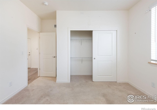 unfurnished bedroom with a closet and light colored carpet