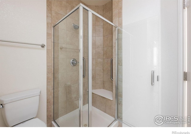 bathroom featuring toilet and a shower with shower door