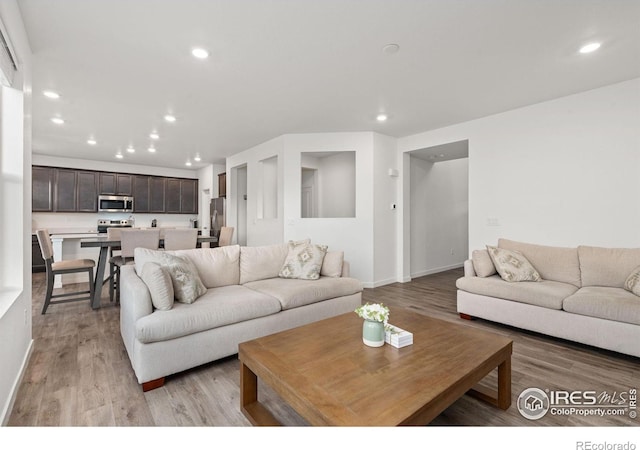 living room with light wood finished floors, baseboards, and recessed lighting