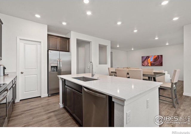 kitchen featuring dark brown cabinetry, recessed lighting, a sink, light wood-style floors, and appliances with stainless steel finishes