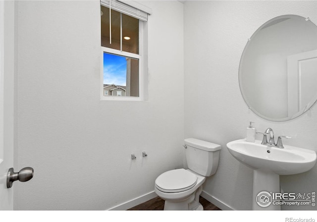 bathroom with toilet, baseboards, and wood finished floors