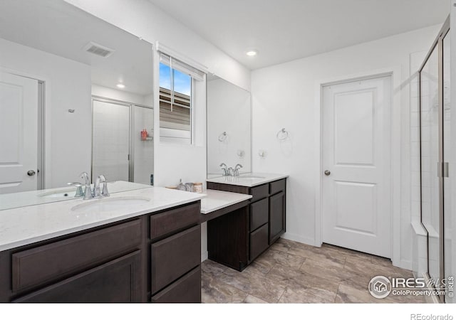 bathroom featuring a stall shower, visible vents, two vanities, and a sink